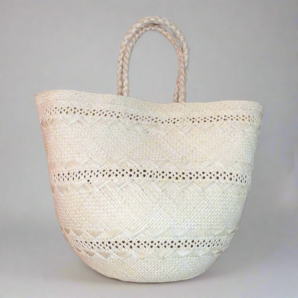 beige woven tote bag with braided handles on a gray background