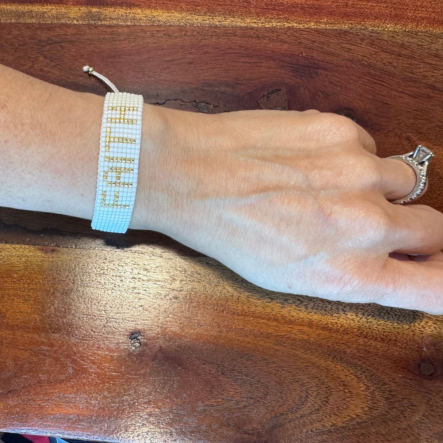 Hand wearing a beaded bracelet on a wooden surface