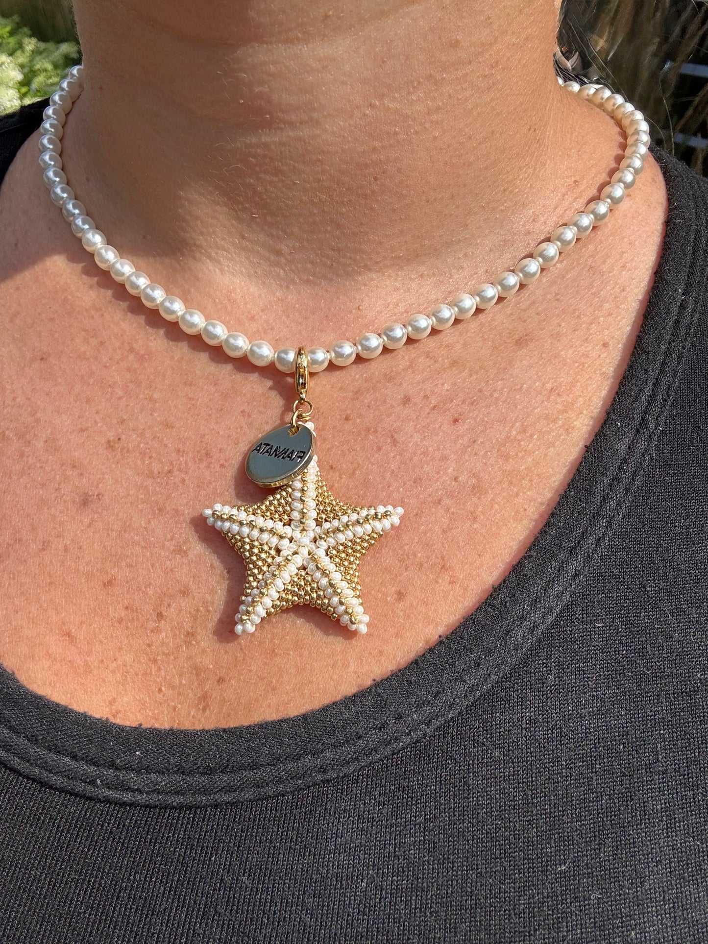 Pearl necklace with a starfish pendant worn by a person