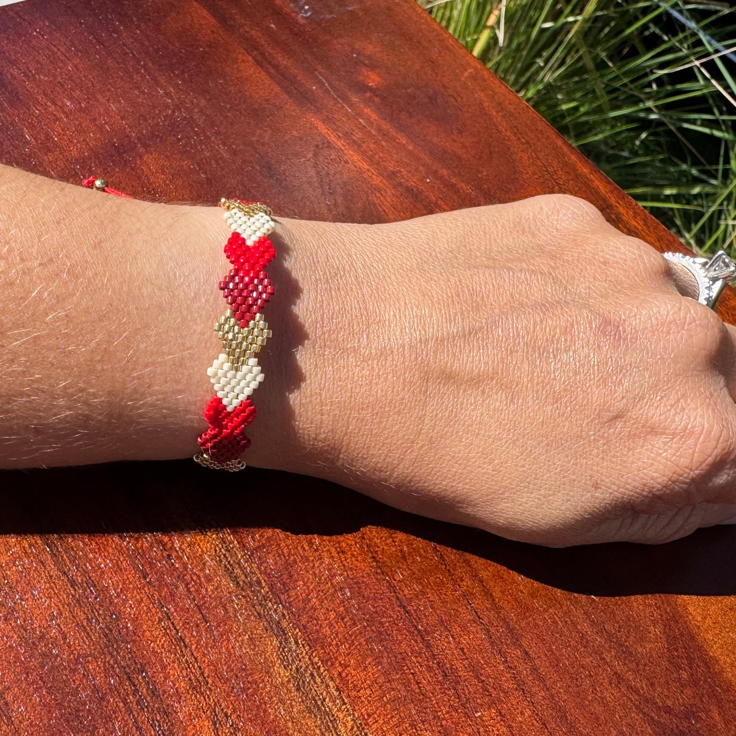 Close-up of a wrist wearing a red and white beaded bracelet