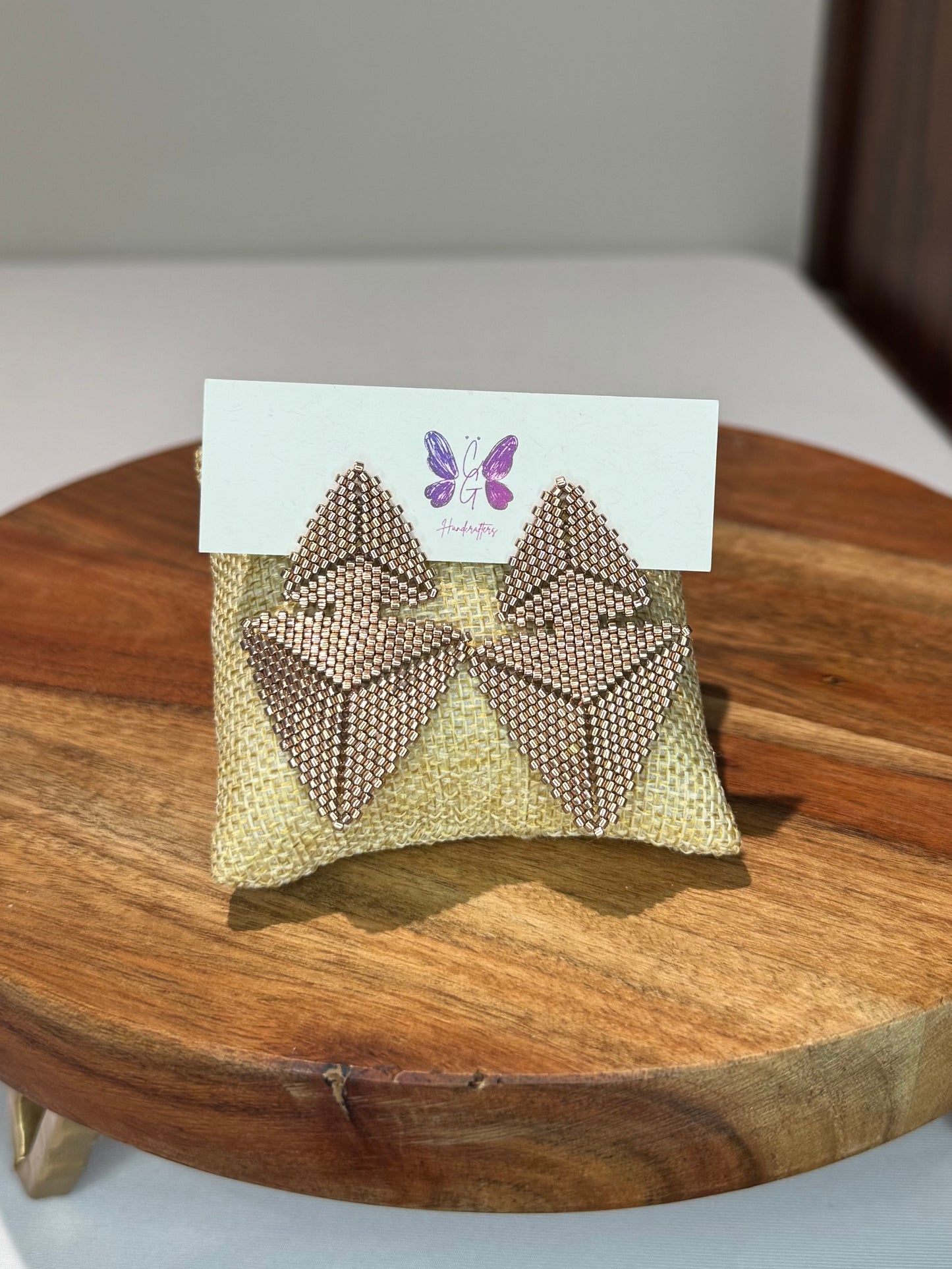 Gold bow-shaped earrings on a card with a triangle design