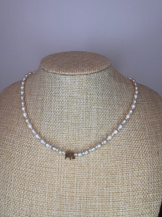 A freshwater pearl necklace with a silver pendant in the shape of an elephant, displayed on a mannequin.