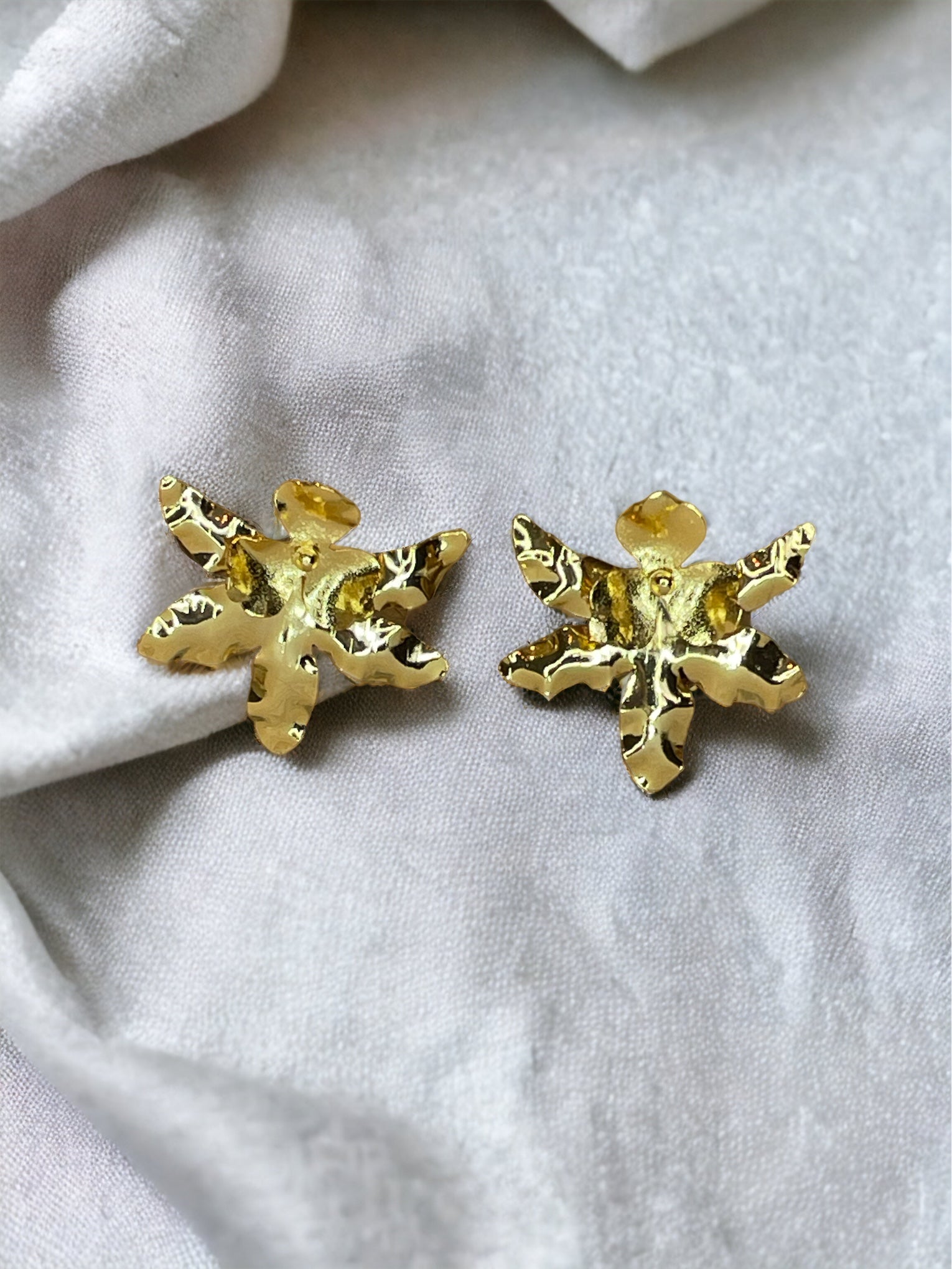 A pair of gold-plated bronze stud earrings designed to resemble an orchid flower.