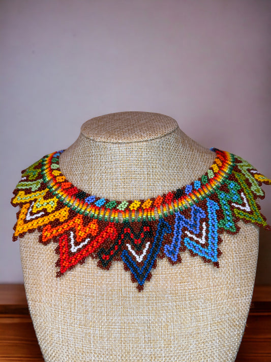 A colorful beaded necklace displayed on a mannequin bust, featuring a variety of geometric patterns.