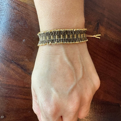 Hand wearing a beaded bracelet on a wooden surface