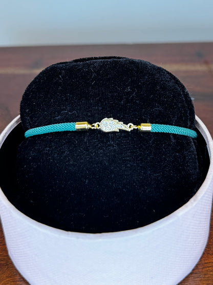 Turquoise bracelet with gold clasp on a black cushion in a white box