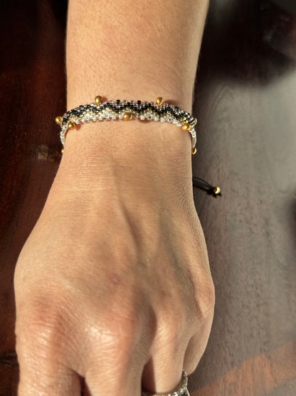 Close-up of a hand wearing a beaded bracelet with a blurred background
