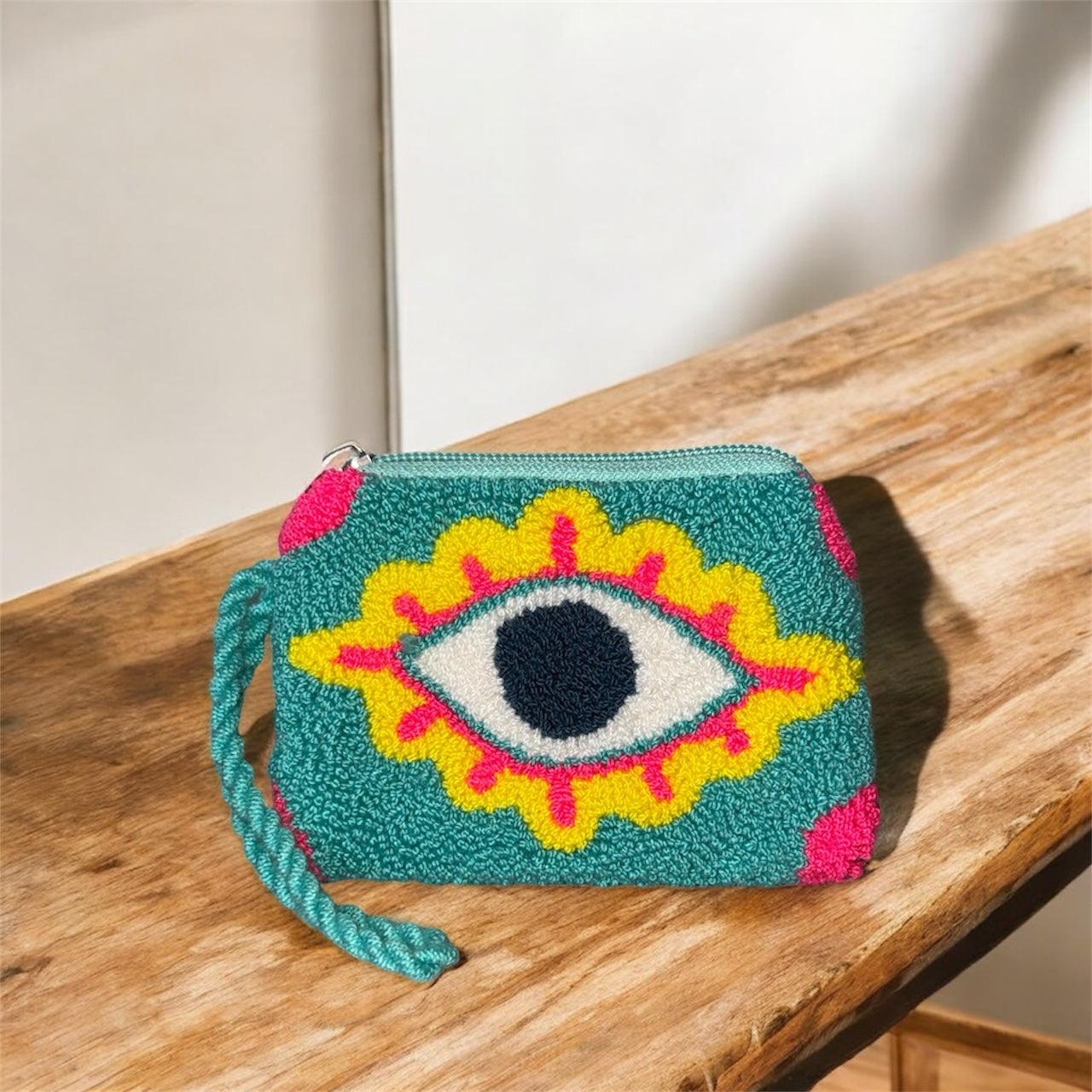 Colorful woven pouch with eye design on a wooden surface