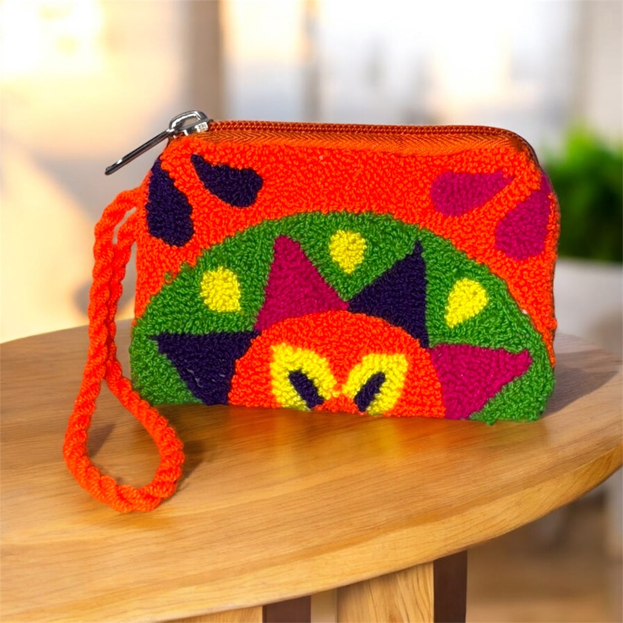 Colorful handcrafted pouch with geometric patterns on a wooden surface
