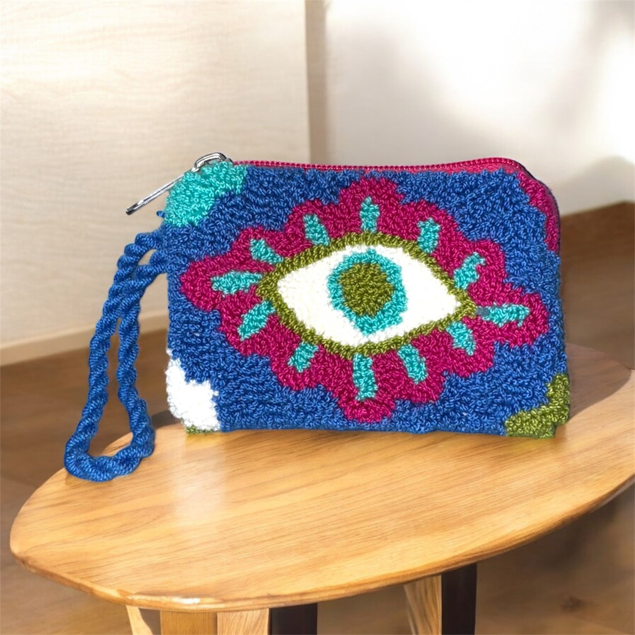 Colorful crochet pouch with eye design on a wooden surface