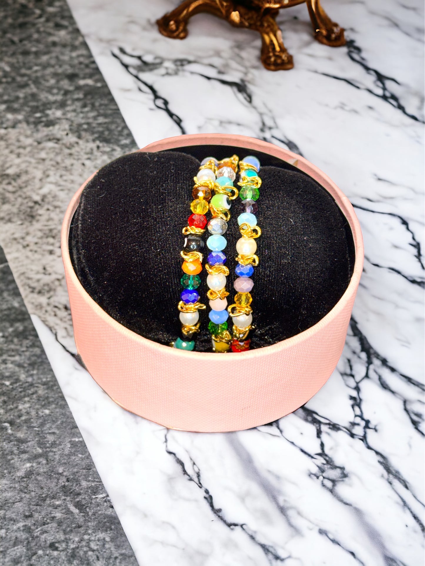 A colorful beaded bracelet displayed in a box, featuring a variety of colored gemstones and crystals.