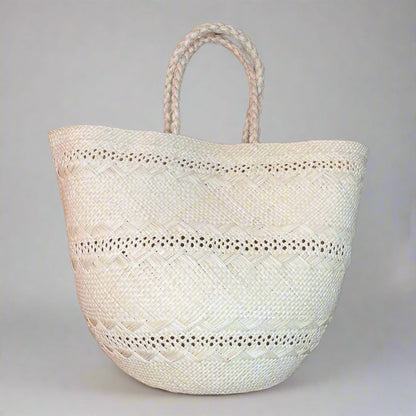 beige woven tote bag with braided handles on a gray background
