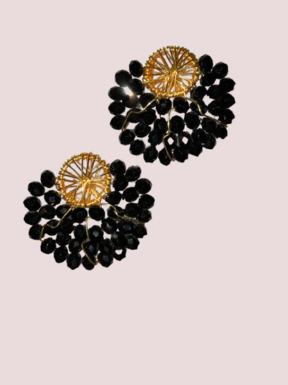 A pair of black and gold colored earrings with a geometric pattern and dangling acrylic beads.