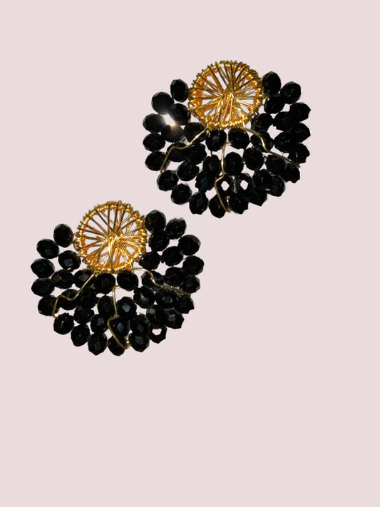 A pair of black and gold colored earrings with a geometric pattern and dangling acrylic beads.