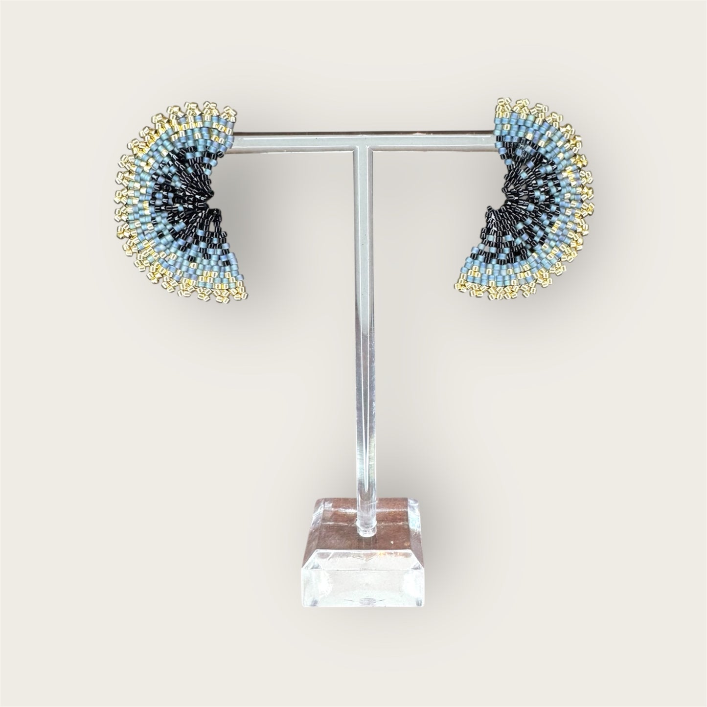 Pair of beaded earrings on a clear stand against a white background