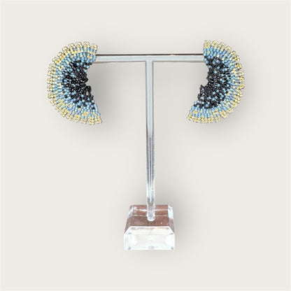 Pair of beaded earrings on a clear stand against a white background