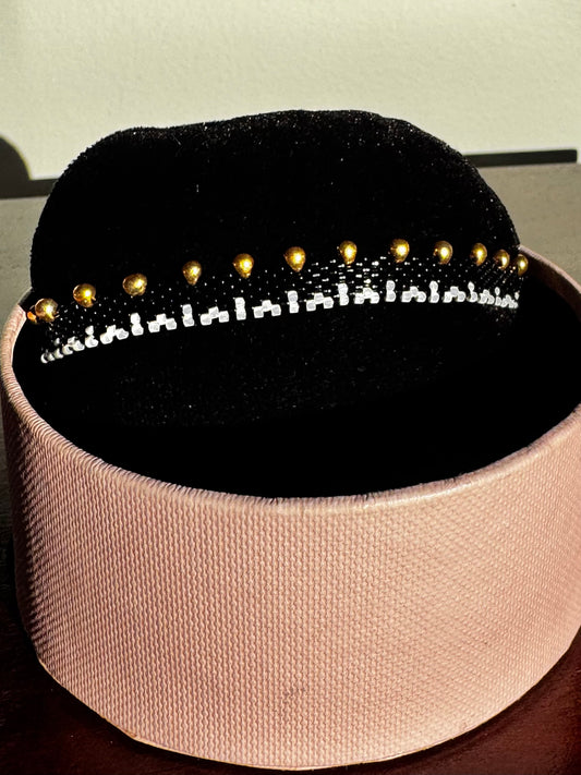 Black beaded headband with gold beads on a pink cushion