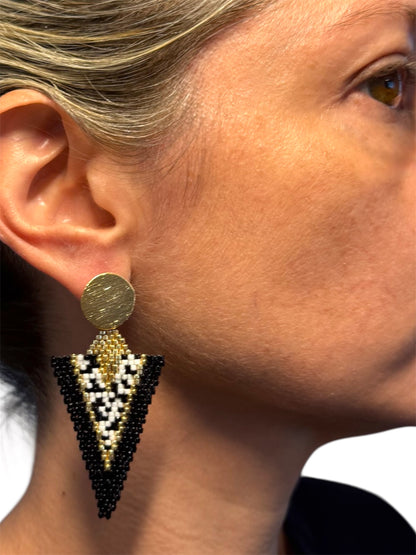 Close-up of a woman wearing a gold and black beaded earring.