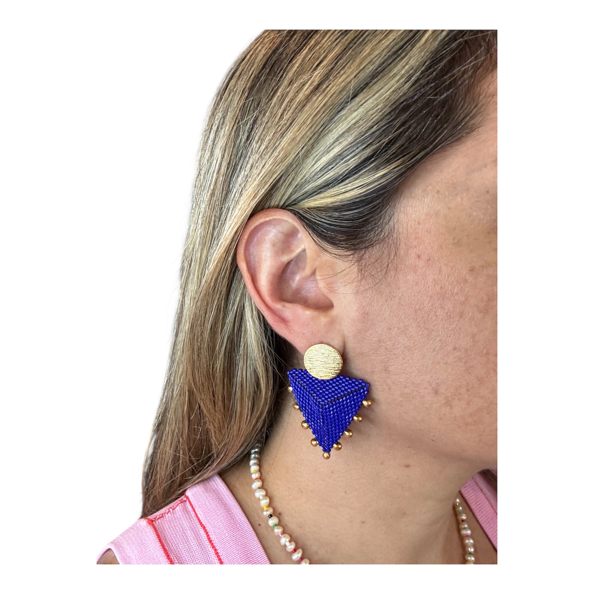Blue triangle-shaped earrings worn by a person with a white background