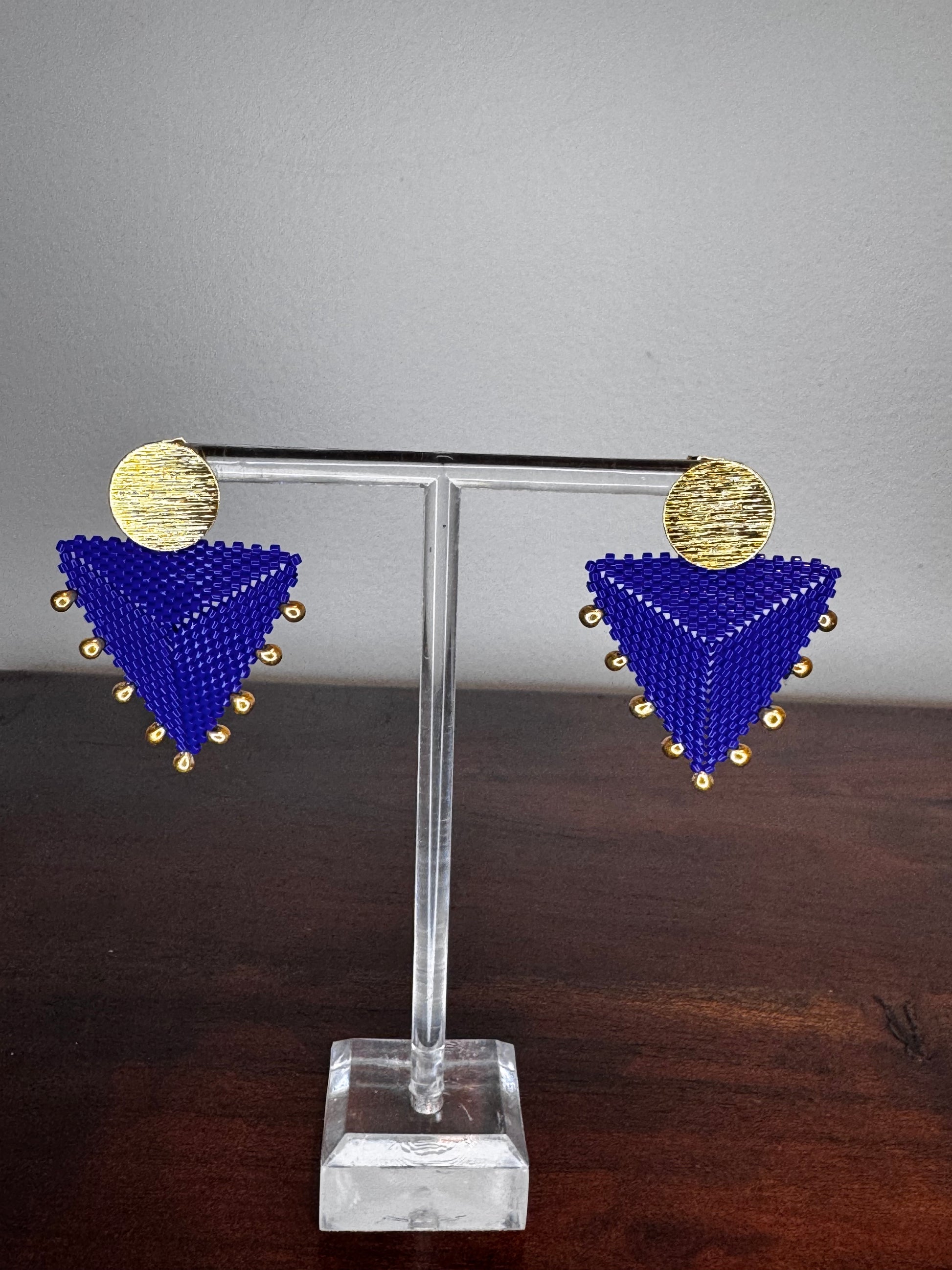 Decorative wall hook with blue and gold geometric design on a gray and wooden background