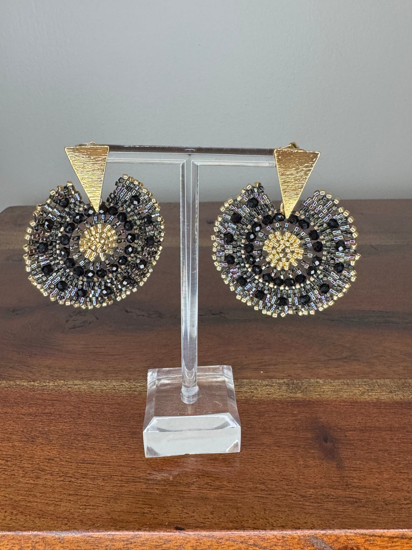 A pair of Spark Earrings displayed on a stand, featuring a hypoallergenic German silver stud and blue acrylic crystals in a circular beaded design.
