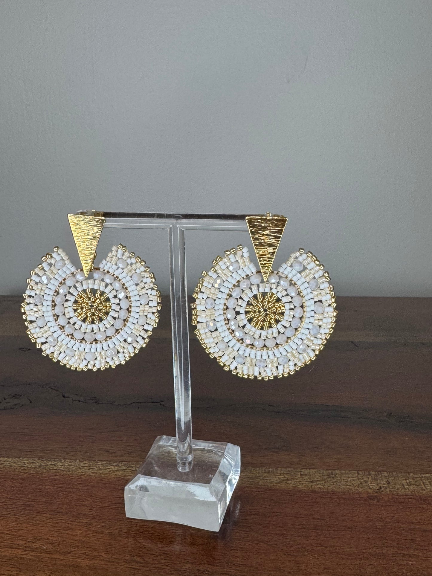 A pair of Spark Earrings displayed on a stand, featuring a hypoallergenic German silver stud and blue acrylic crystals in a circular beaded design.