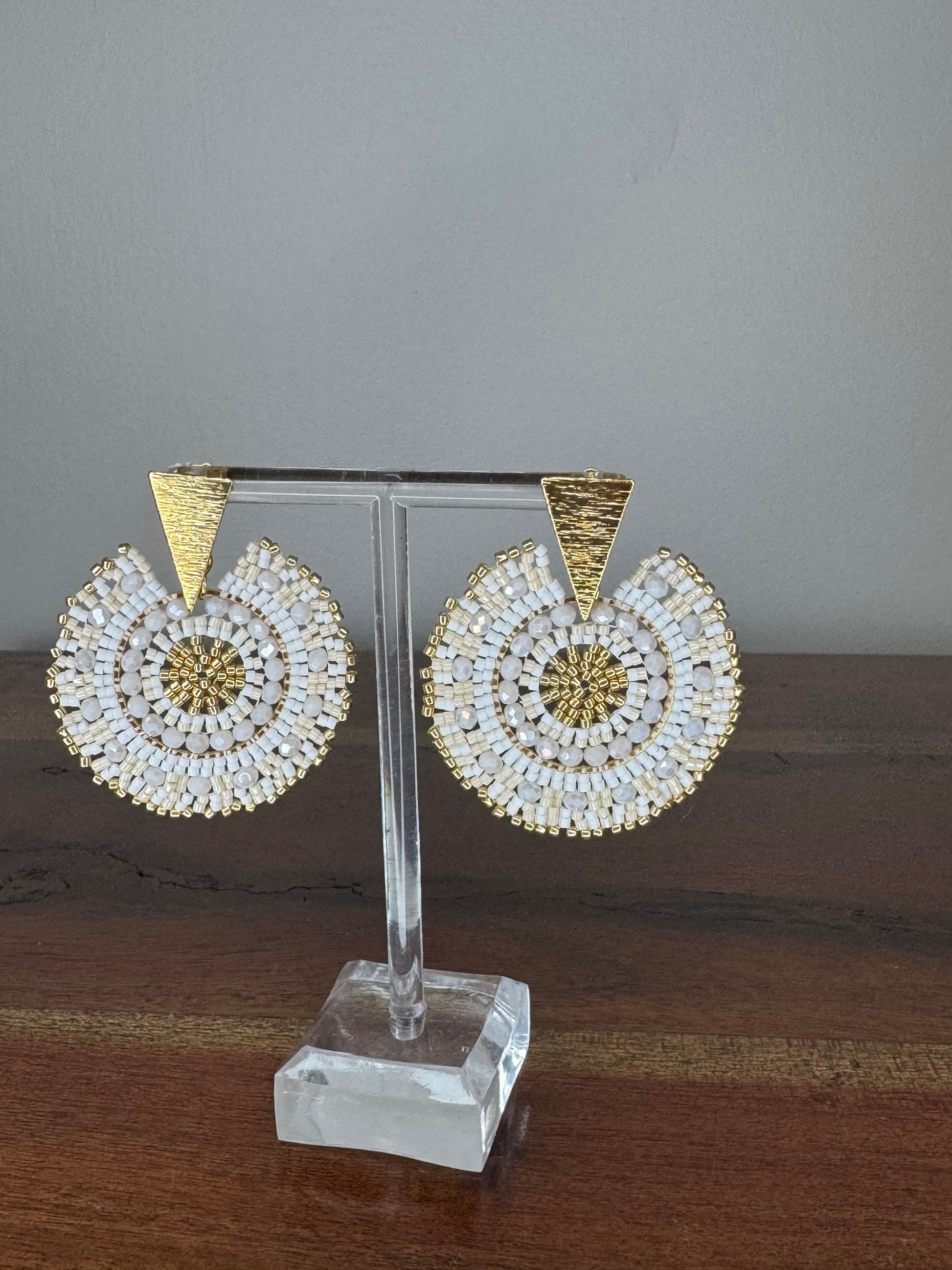 A pair of Spark Earrings displayed on a stand, featuring a hypoallergenic German silver stud and blue acrylic crystals in a circular beaded design.