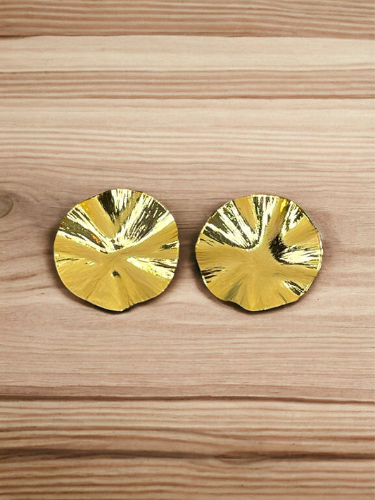 A pair of gold-plated bronze wrinkle earrings with a round shape, displayed on a wooden surface.