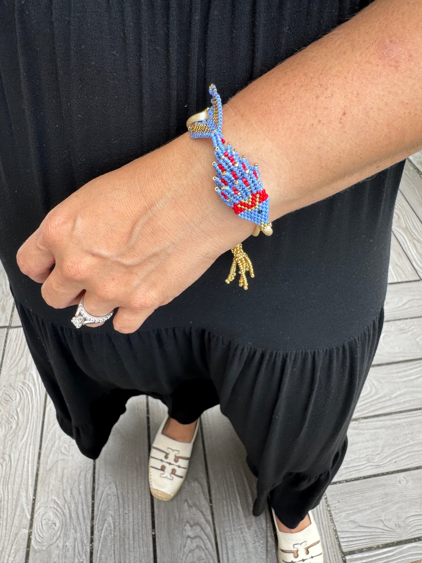 Person wearing a colorful beaded bracelet on a wooden floor