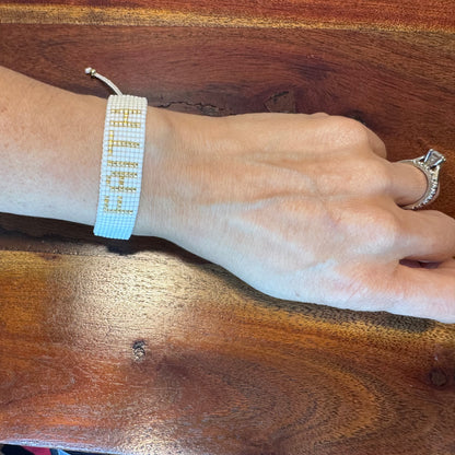 Hand wearing a beaded bracelet on a wooden surface