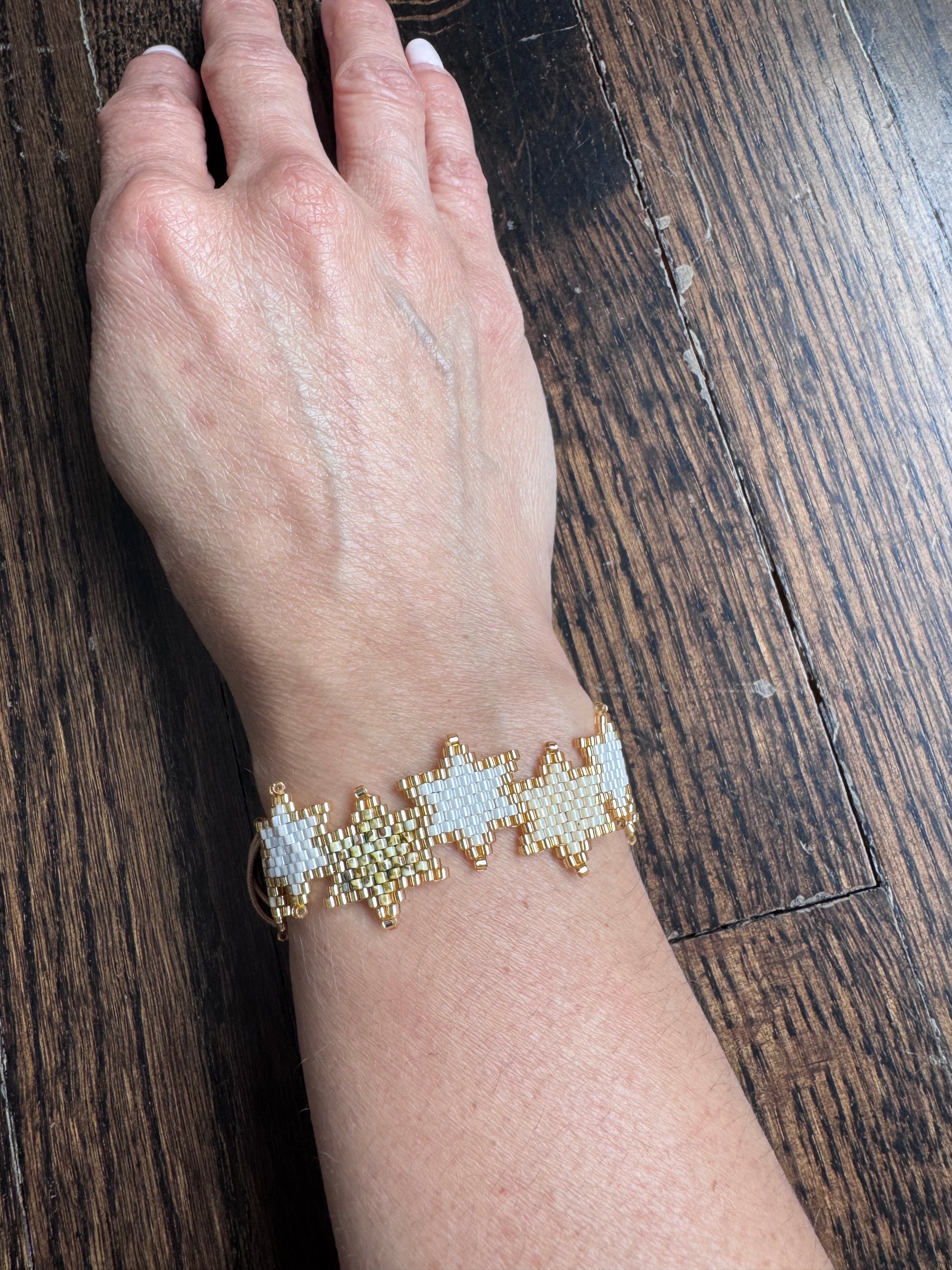 Hand wearing a beaded bracelet on a wooden surface