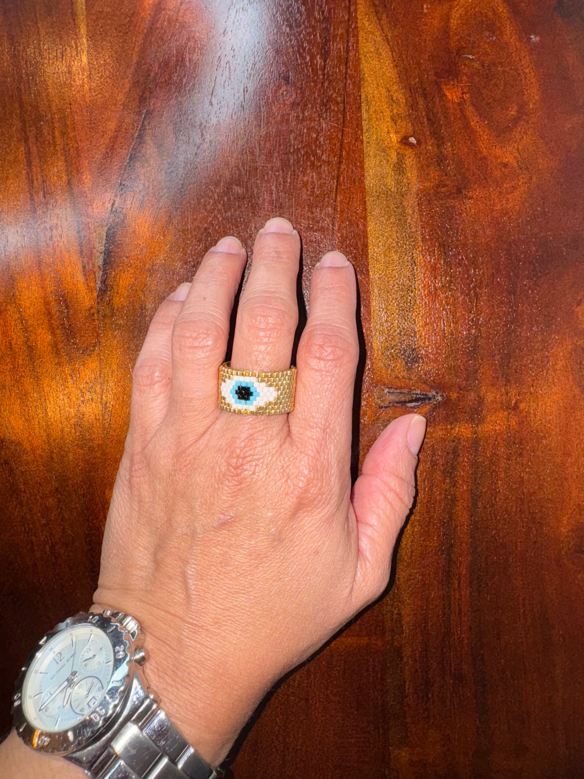 Hand wearing a ring with a blue stone on a wooden surface
