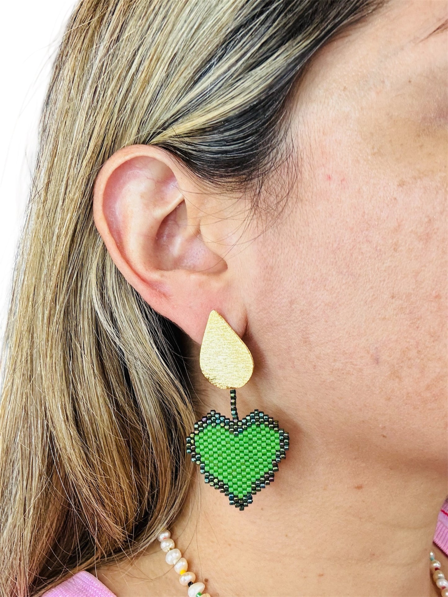 Close-up of ear wearing a green beaded heart earring.