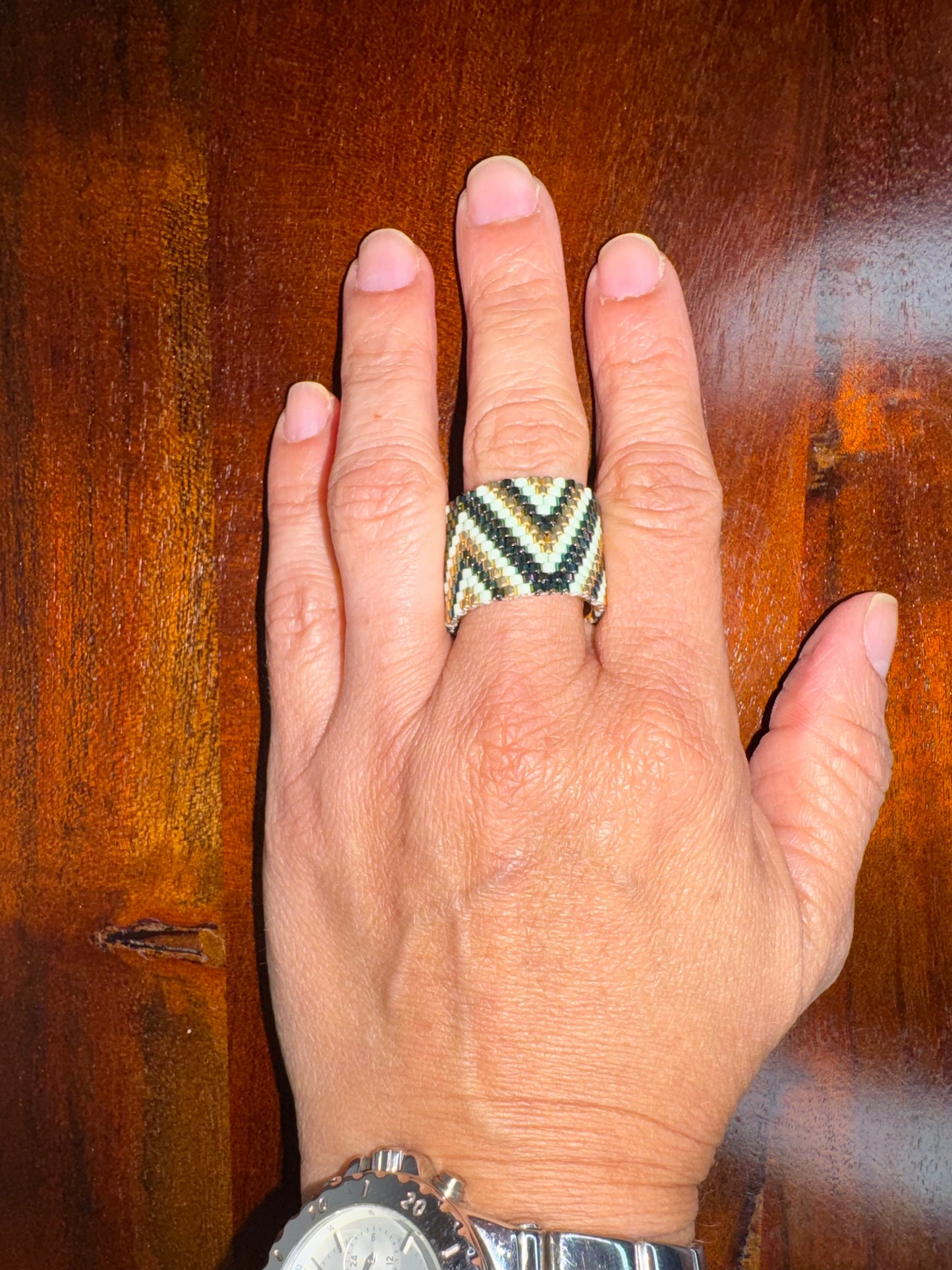 Hand wearing a patterned ring with a wooden background