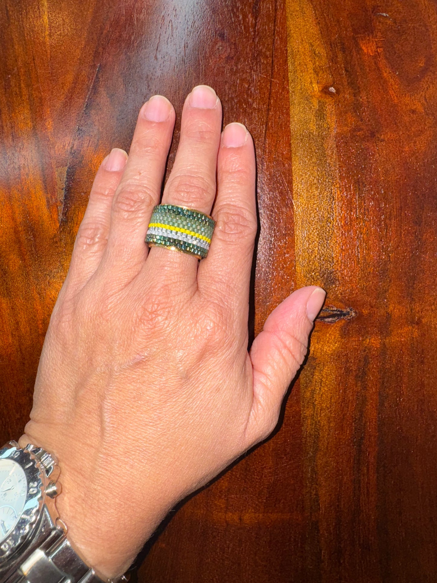 Hand wearing a ring with a wooden background