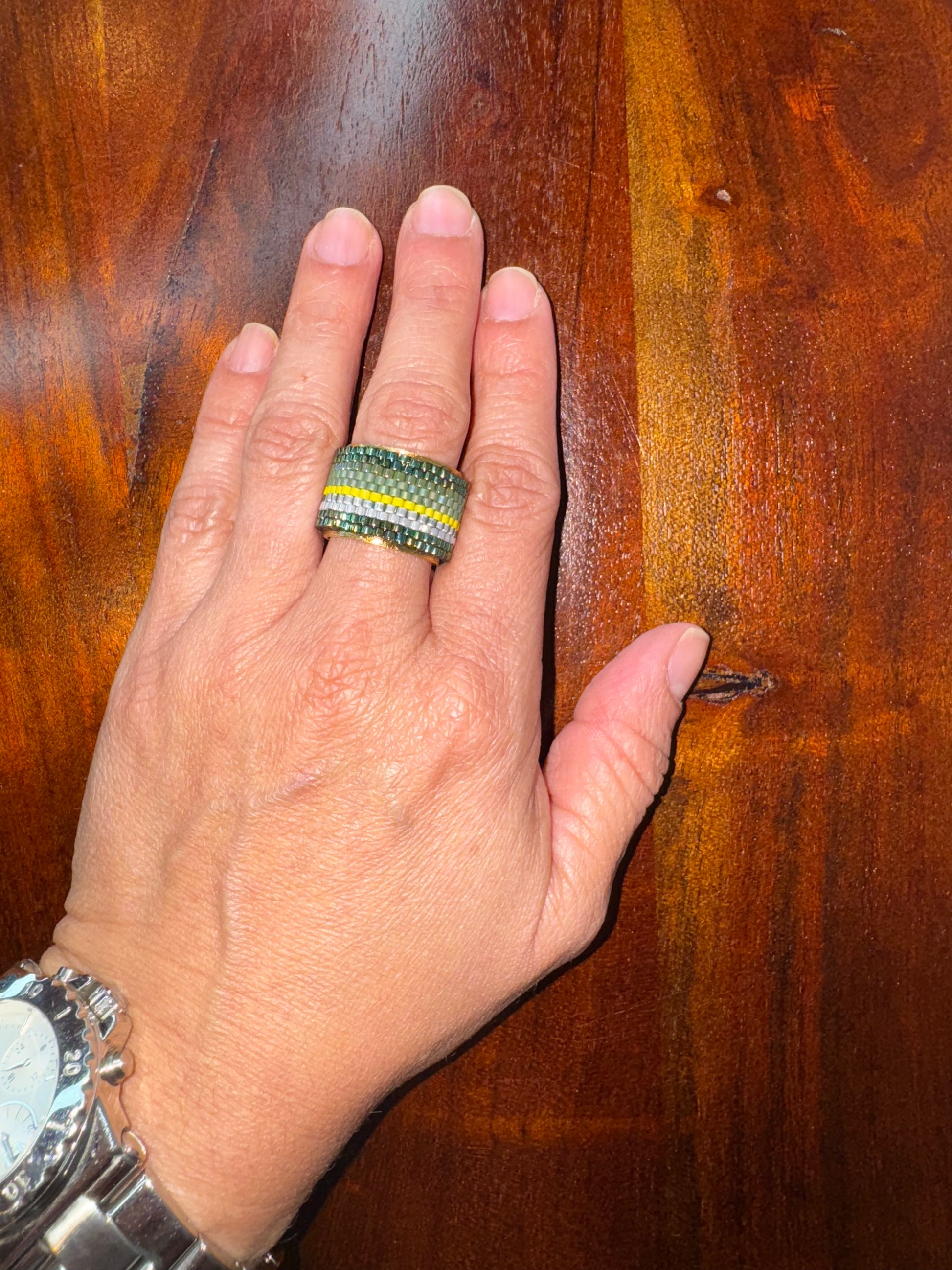 Hand wearing a ring with a wooden background