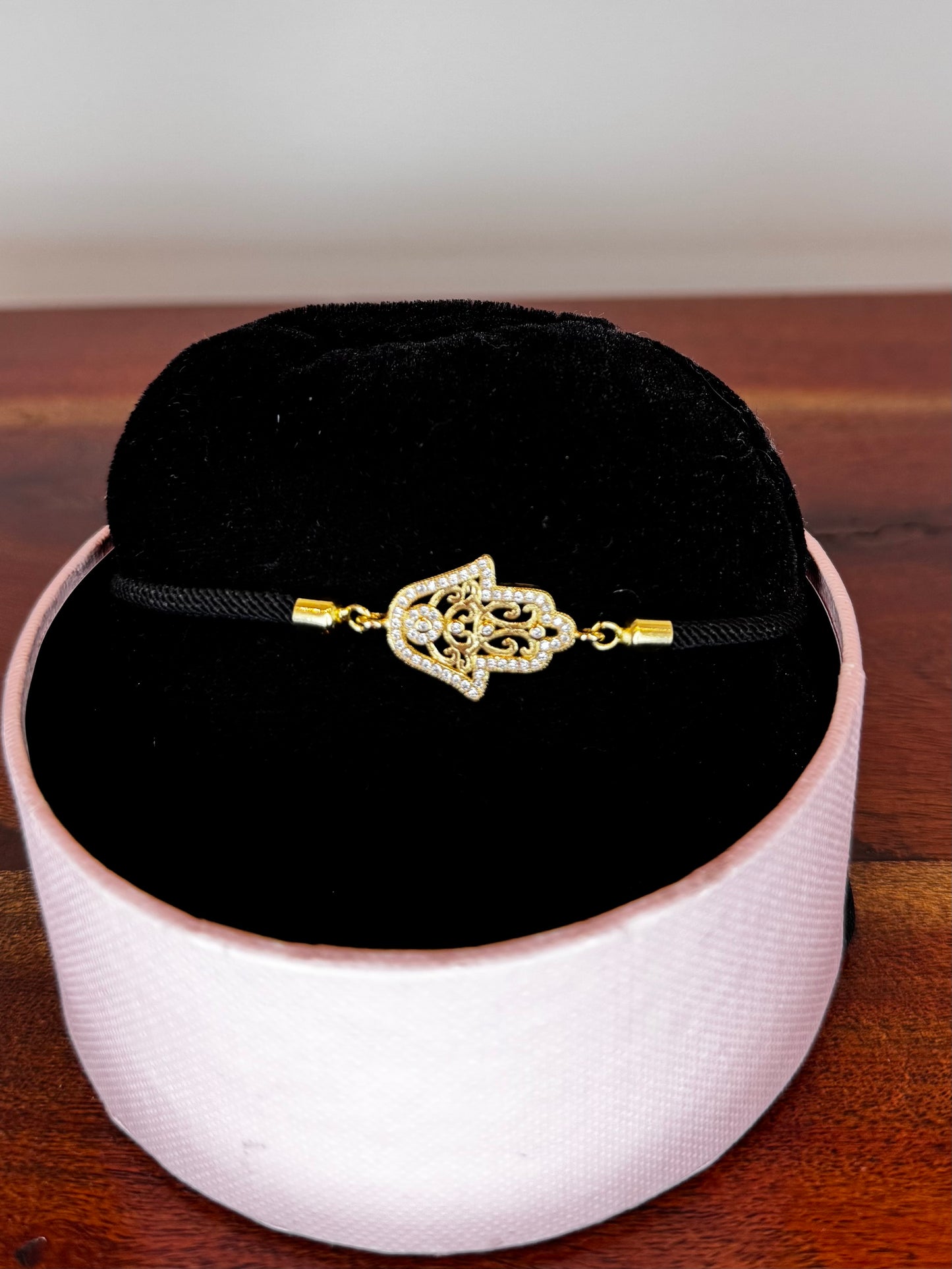 Gold bracelet with a decorative clasp on a black cord