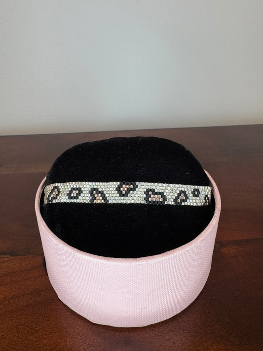 Black and white headband with decorative pattern on a pink cushion against a neutral background
