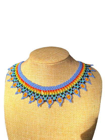 A colorful beaded necklace displayed on a mannequin bust, featuring a vibrant mix of pastel colors.