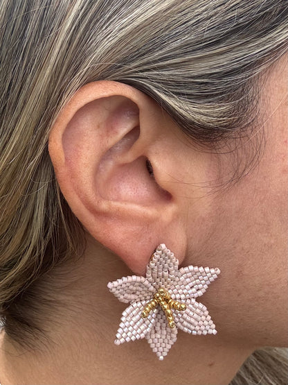 Close-up of an ear wearing a pink beaded flower earring with gold accents.
