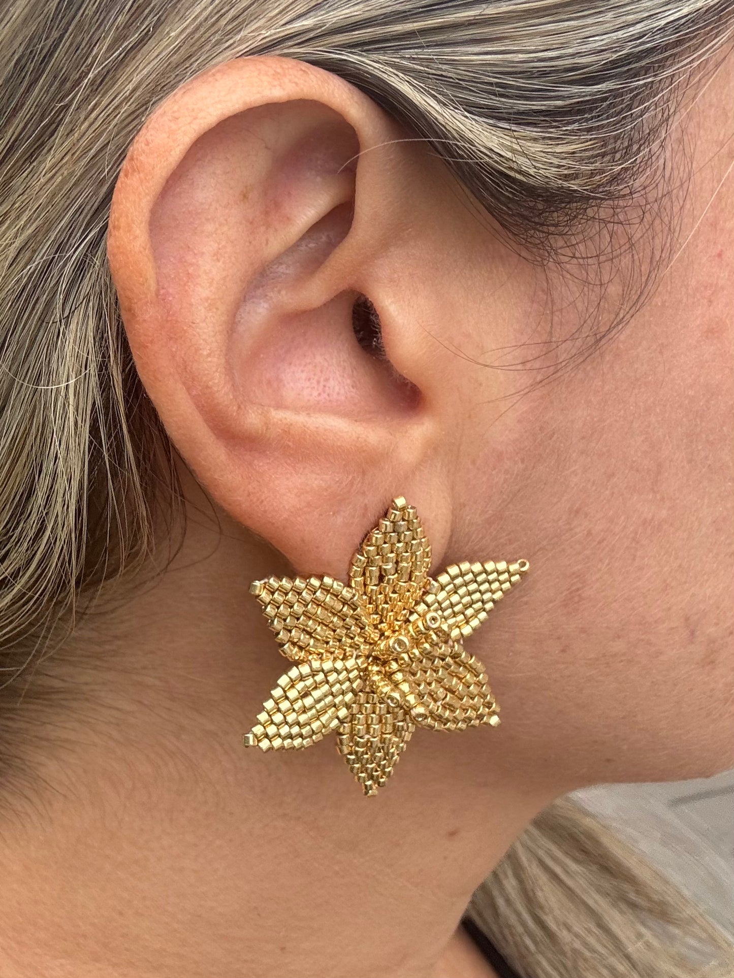 Close-up of a person wearing a gold star-shaped earring.