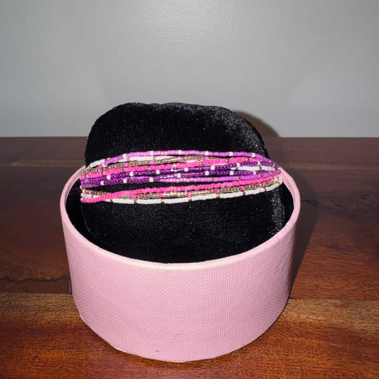 Pink jewelry box with beaded bracelets on a wooden surface
