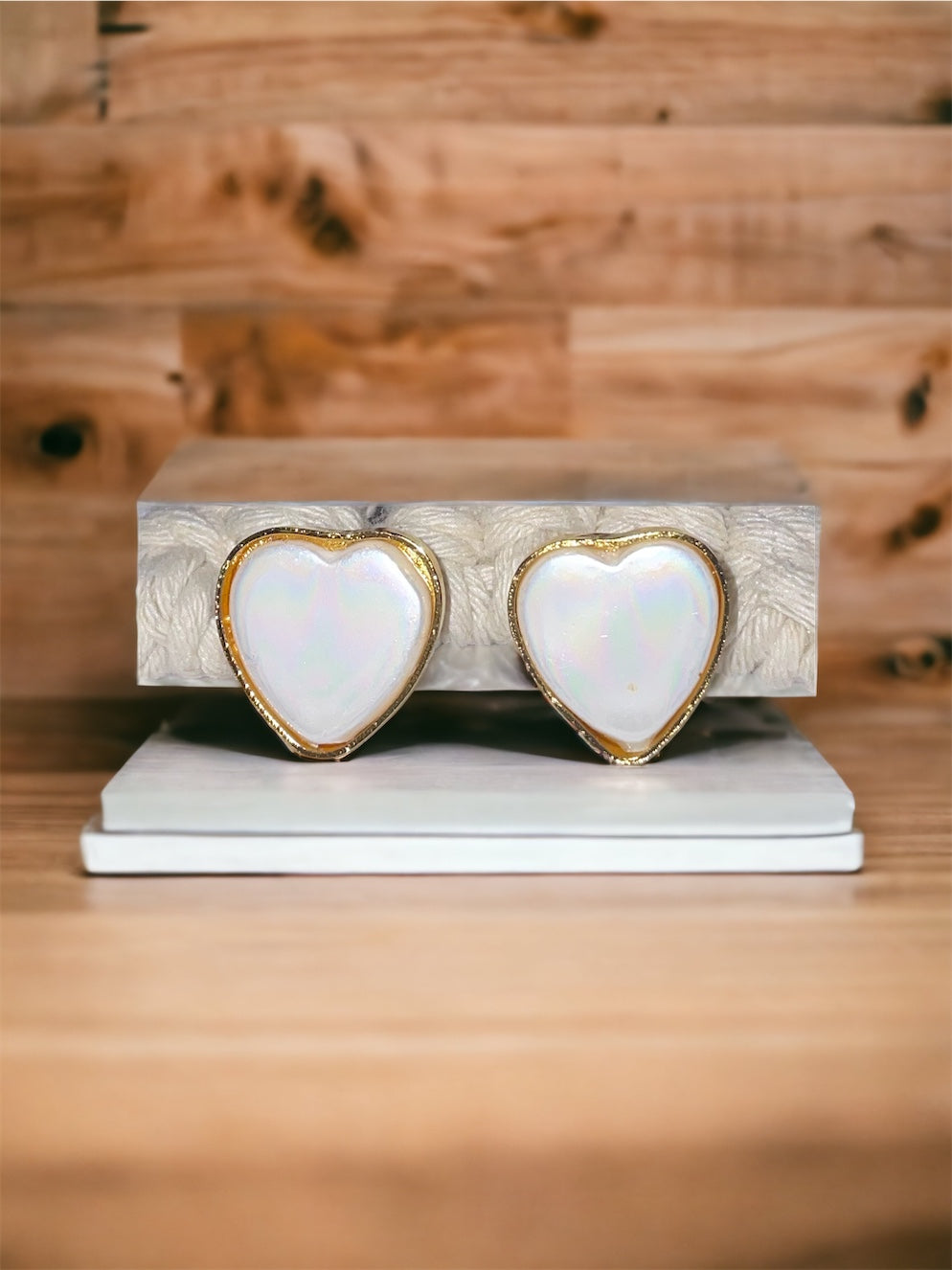 A pair of heart-shaped nacre earrings with gold plating, displayed on a flat surface.