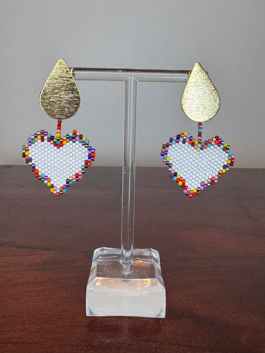 A pair of Miyuki earrings displayed on a stand, featuring a white beaded design with a gold-colored drop-shaped top.