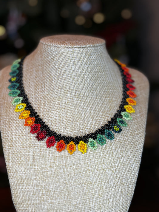 A multicolored beaded necklace with a black border displayed on a mannequin bust.