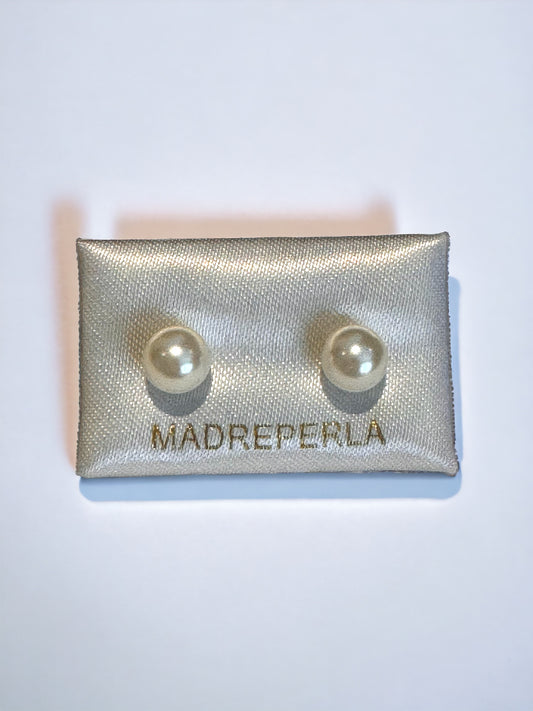 A pair of beige natural colour pearl stud earrings with a golden stud style, placed on a flat surface.