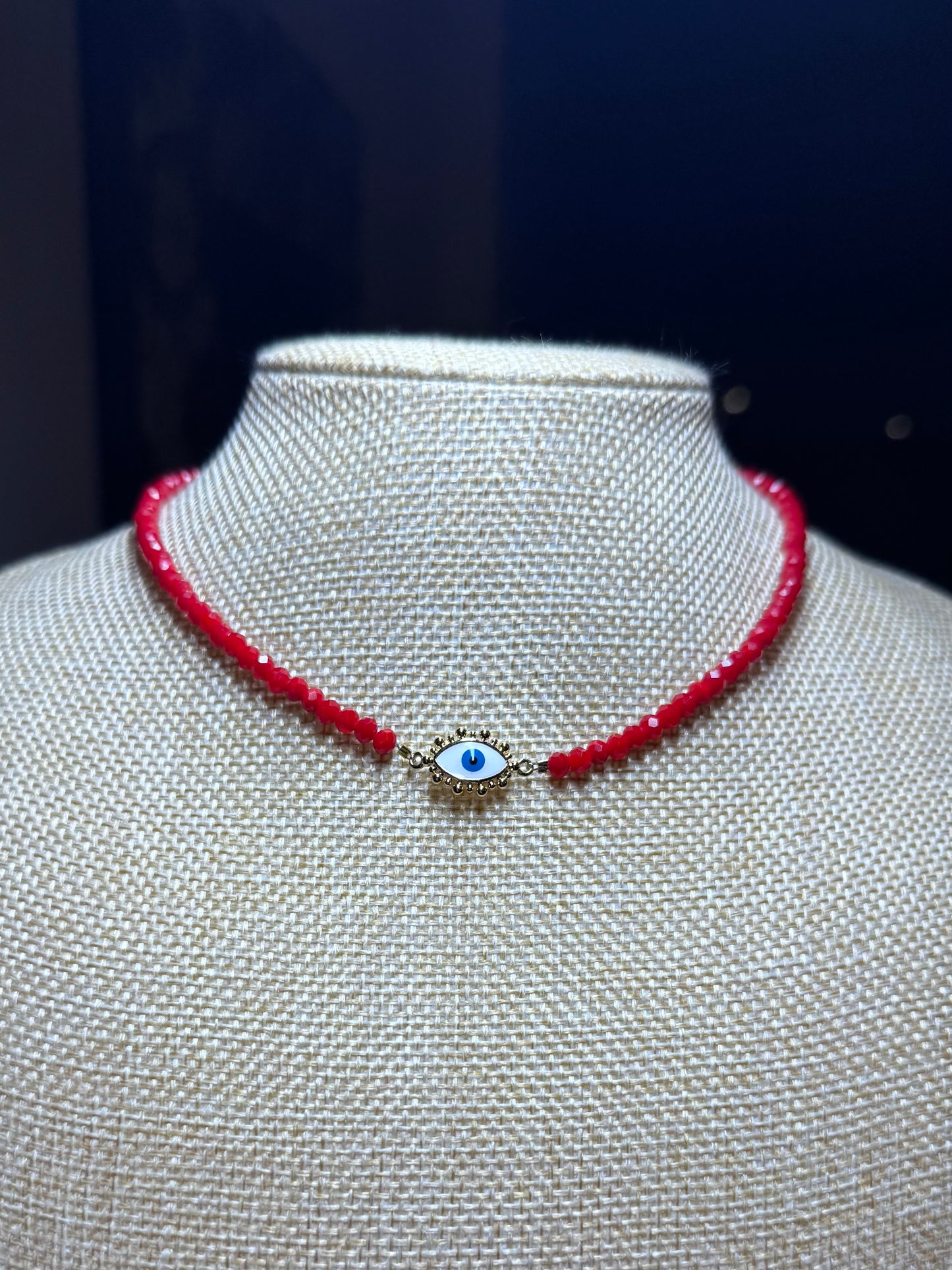 Red beaded necklace with a blue evil eye charm