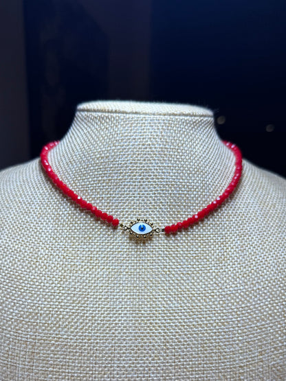 Red beaded necklace with a blue evil eye charm