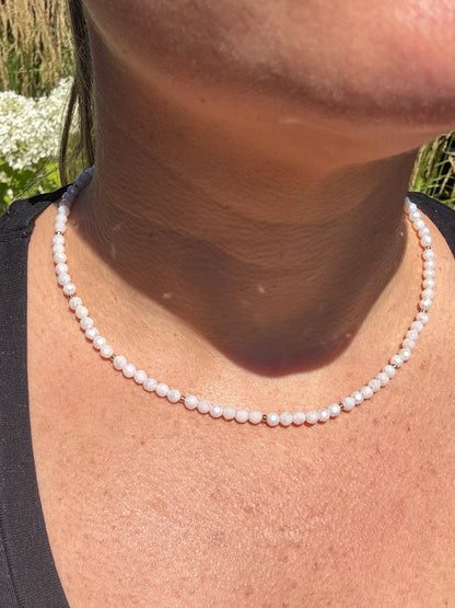 Pearl necklace worn by a person with a blurred natural background