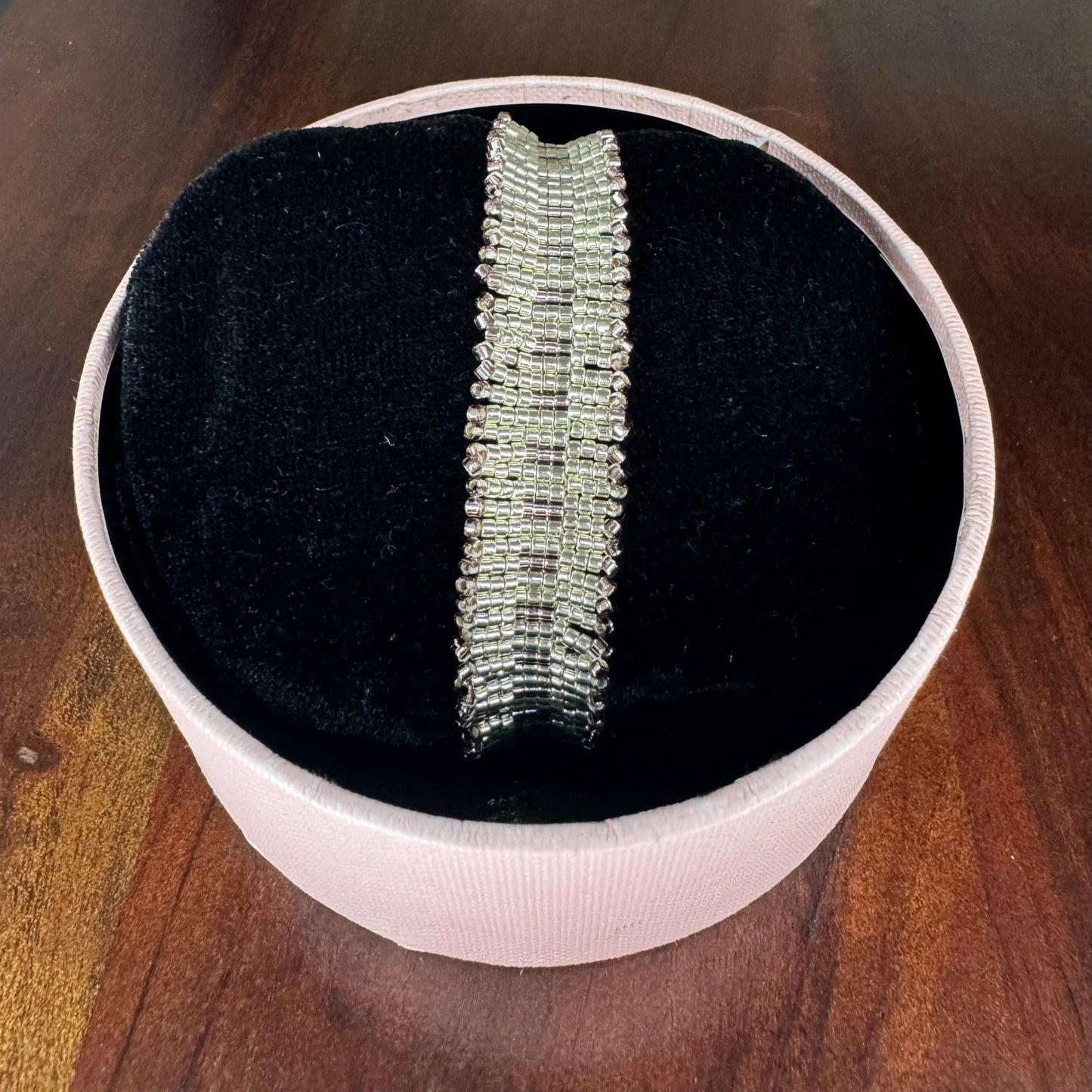 Silver bracelet in a white box on a wooden surface